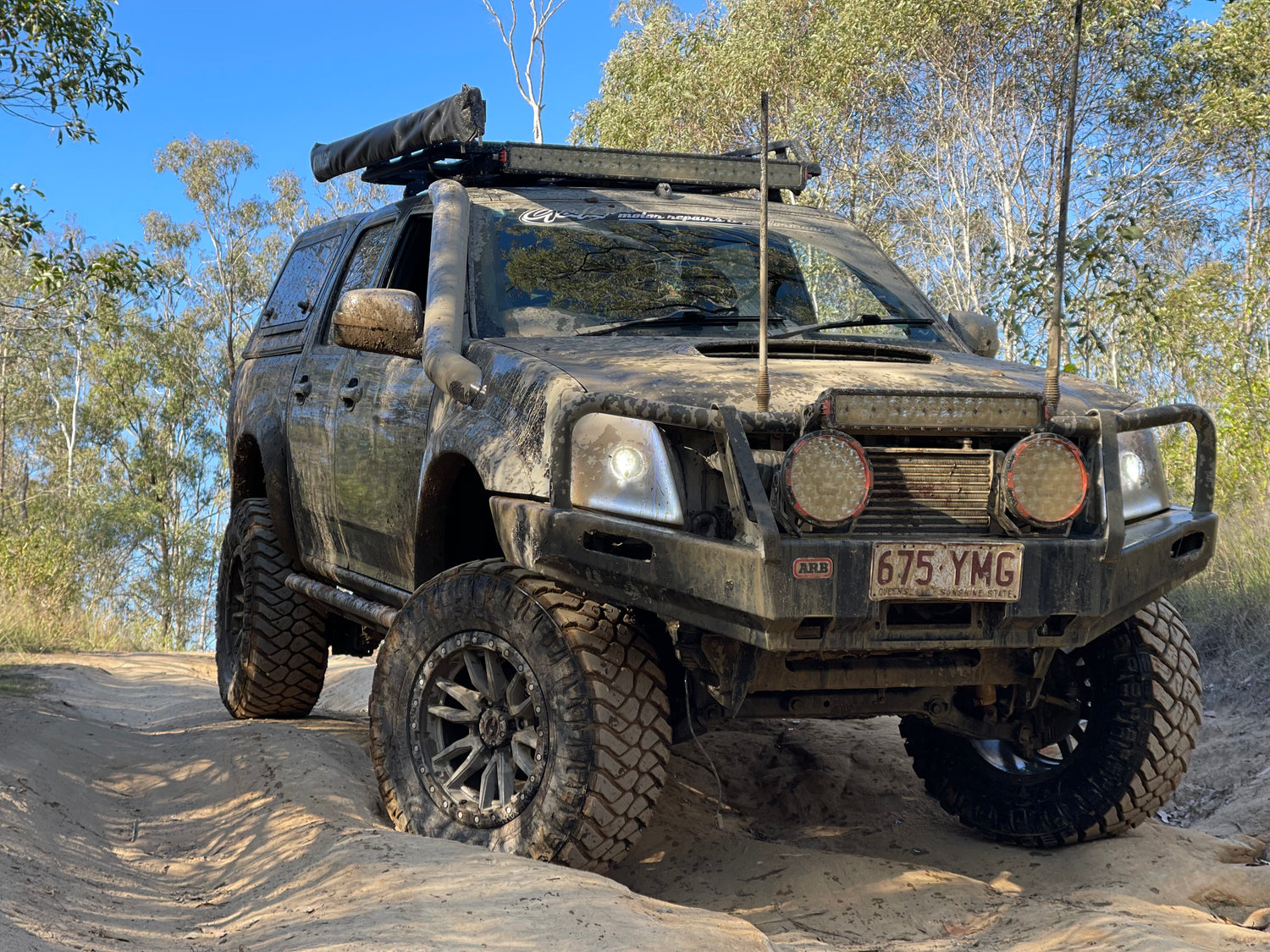 Low angle of a sandy heavily-modified Holden Colorado RC parked in a sand dune.